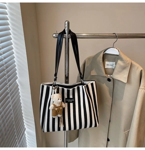 Détail du sac cabas en toile rayée avec garniture en cuir noir et breloque ours mignon