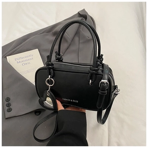 Détail du sac Boston noir mat avec doubles poignées et breloque miroir en cœur