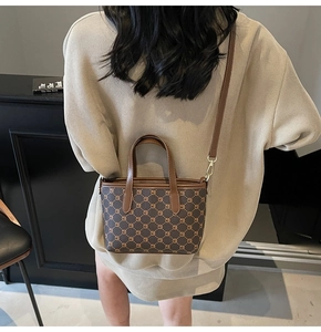 Détail d'un sac cabas marron à monogramme avec poignées en cuir et bandoulière dorée