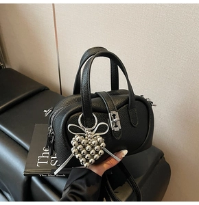 Détail du sac en cuir noir avec fermoir métallique argenté et breloque coeur
