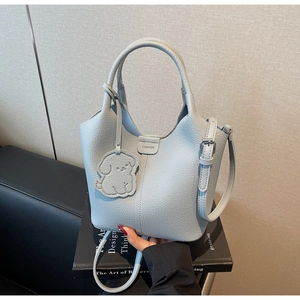 Close-up of light blue lychee pattern leather bucket bag with a dog-shaped charm