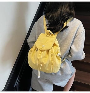Vista dettagliata dello zaino in nylon giallo brillante indossato dal modello