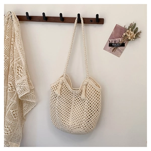 Close-up of beige crochet tote bag with hollow mesh design and tassel details