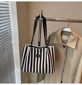 Détail du sac cabas à rayures noires et blanches avec étiquette en cuir et fines bretelles