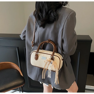 Dettaglio della borsa Boston crema e marrone con nastro in pizzo e logo argento sul modello