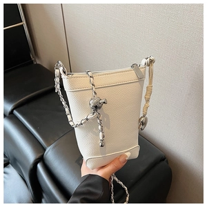 Détail du sac seau en cuir litchi blanc avec chaîne argentée et texture grainée