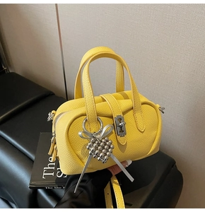 Détail du sac bowling en cuir jaune à motif litchi avec pendentif raisin et ruban argent