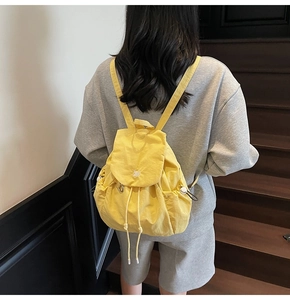 Dettaglio dello zaino giallo in nylon con coulisse e patta su una modella femminile