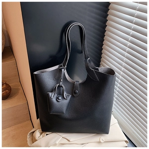 Detail of black pebbled leather tote bag with a matching mini pouch on a stylish staircase