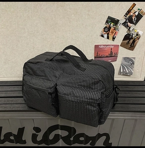 Détail du sac de voyage à carreaux avec deux poches avant et poignées en sangle robustes