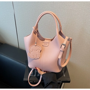 Detail of pink lychee grain bucket bag featuring a cute puppy charm and adjustable strap