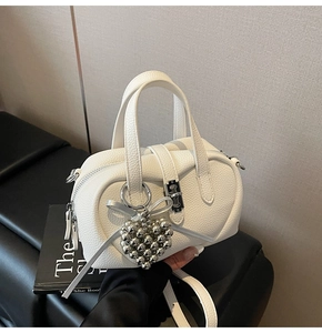 Détail du sac blanc en cuir grainé avec breloques coeur argentées et fermeture à loquet
