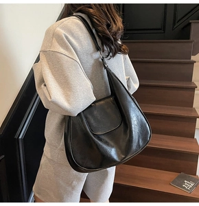 Side view of model wearing a black glossy PU leather hobo bag on a staircase