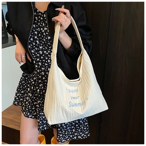 Détail du sac hobo en toile crème avec texture plissée et broderie d'été bleue