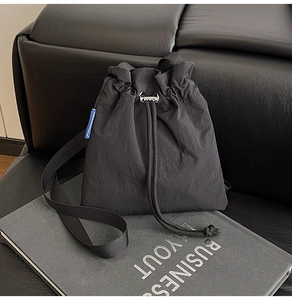 Detail of minimalist black nylon drawstring bag on business book and leather sofa