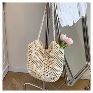 Detailed macro view of beige hollow-out straw woven tote bag with fringe tassels