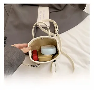 Overhead view showing storage capacity of white bucket bag with cosmetics and lipstick