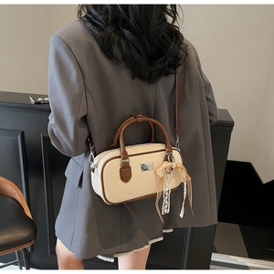 Dettaglio borsa Boston intrecciata beige con manici marroni e ciondolo di perle