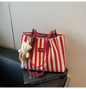 Détail macro du sac cabas en toile à rayures rouges et blanches avec anses en cuir rouge