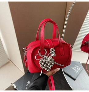 Détail du sac à main rouge en cuir litchi avec fermoir argenté et breloque coeur