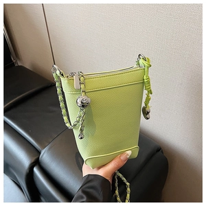 Gros plan du sac seau vert clair montrant la texture grainée et le charme cœur