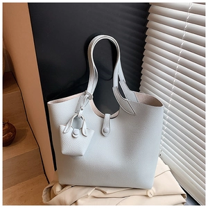 Detail view of light blue lychee pattern leather tote bag with matching mini pouch charm