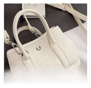 Close-up of white lychee grain leather mini tote showing silver studs and hardware detail