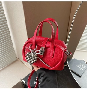 Détail du sac Boston rouge en cuir grainé avec breloque cœur et serrure argentée