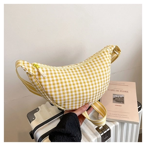 Detail of yellow checkered half-moon crossbody bag with striped strap and zipper close