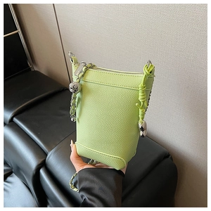 Détail du sac seau vert vif en cuir grainé avec chaîne argentée et breloques mignonnes