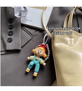 Schattige cartoon meisje hanger met blauwe overal en parelketting aan beige handtas