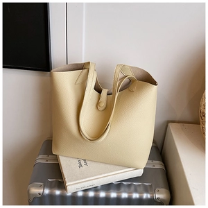Macro view of beige tote bag showing textured pebble leather and buckle closure detail