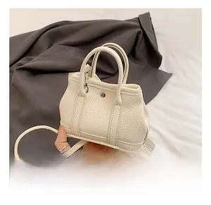 Close-up of beige pebble grain leather mini bucket bag with sleek dual handles