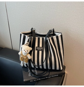 Vue détaillée du cabas à rayures avec logo en cuir et breloque ours en peluche mignon