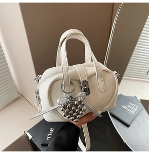 Détail du sac polochon blanc en cuir grainé avec charm cœur perlé et nœud décoratif