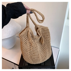 Close-up of beige crochet hollow tote bag featuring decorative fringe and handwoven rope handles