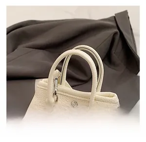 Detail view of white lychee grain leather handbag with curved handles and silver hardware