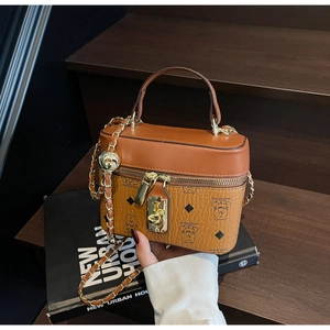 Detail view of vintage brown bucket bag with bear print and gold chain strap on wooden stairs