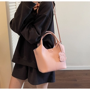 Pink bucket bag with litchi texture featuring a cute dog charm and Monday logo