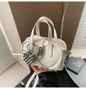 Gros plan du sac Boston blanc crème avec texture grainée et pendentif en cœur