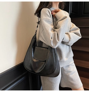 Side view of a vintage black leather hobo bag worn by a model on a stairway