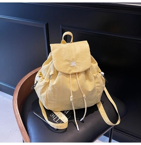 Dettaglio dello zaino giallo chiaro con coulisse e logo su poltrona in pelle nera
