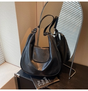 Detail of black vintage half-moon bag with cracked leather texture and adjustable strap