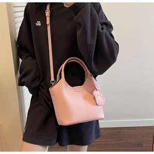 Pink lychee grain leather bucket bag featuring a detachable strap and a dog charm accessory