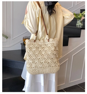 Close-up of hollowed-out straw tote bag showing detailed flower pattern and leather strap