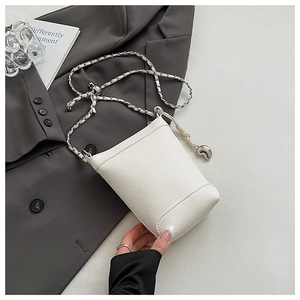 Détail du sac seau blanc en cuir litchi avec bandoulière chaîne argentée et pendentif