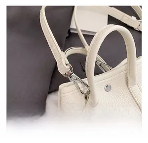 Detailed close-up of premium silver metal hooks and white lychee leather texture on handbag