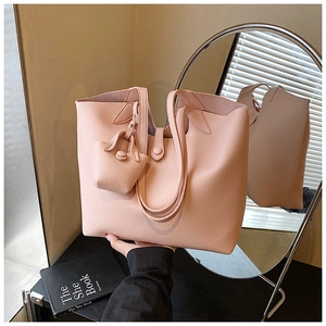 Close-up of pink lychee grain leather tote bag featuring a magnetic clasp and mini pouch
