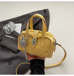 Détail du sac à main en cuir grainé jaune avec fermoir argenté et breloque cœur