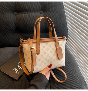 Détail d'un mini sac cabas chic avec motifs monogrammes vintage et pendentif en cuir